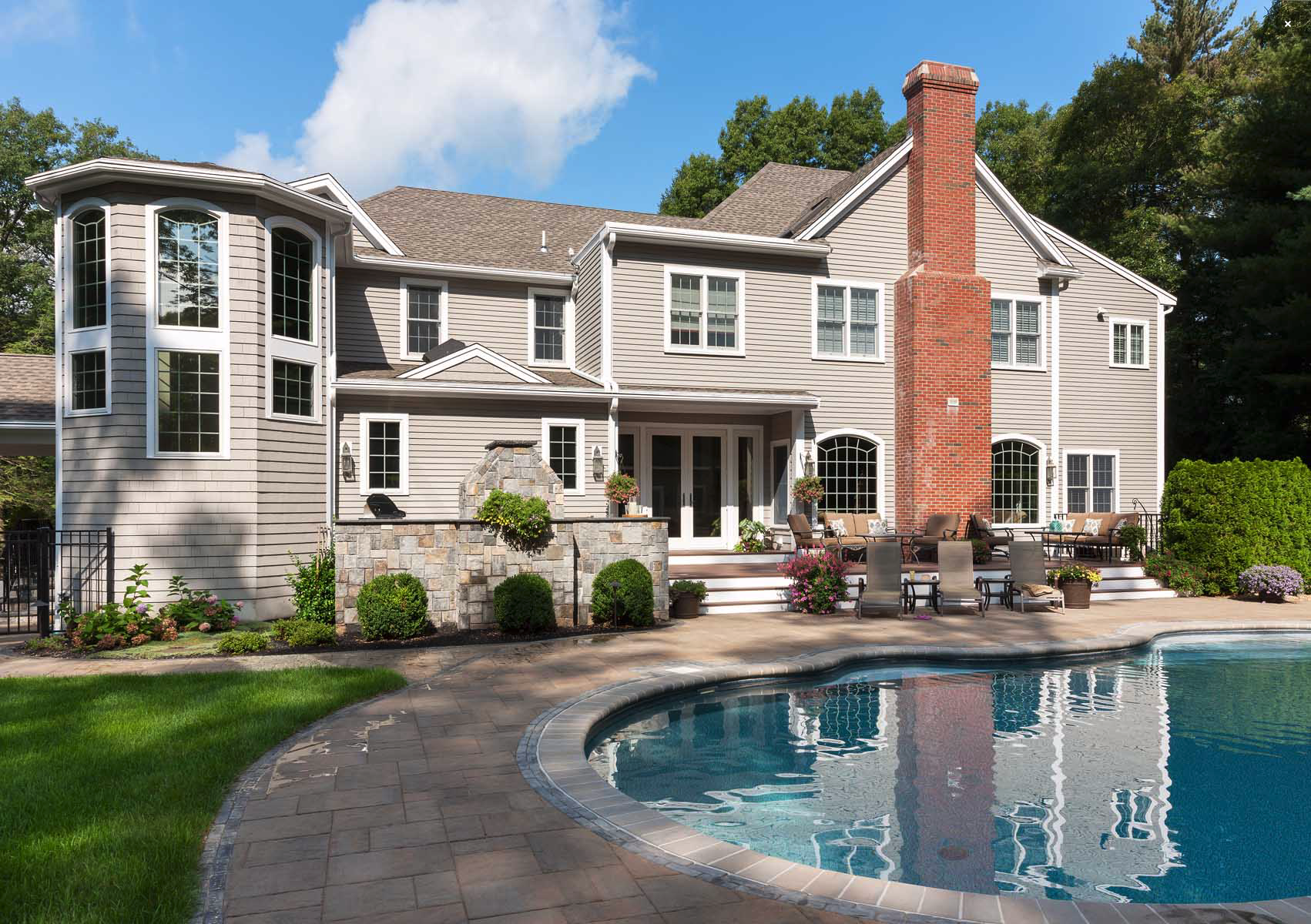 This client opted for the pool, patio and outdoor kitchen trifecta. They added a water feature as well. Notice the green space they allowed for yard games.